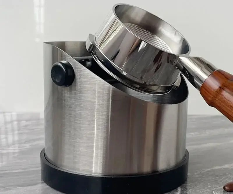A portafilter being knocked out against the Baristo rubber bar
